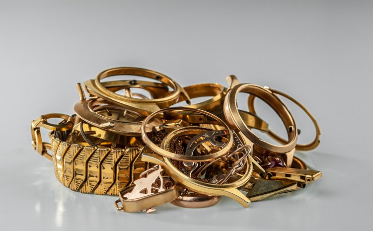 A scrap of gold. Old and broken jewelry watches of gold and gold-plated on a grey background.